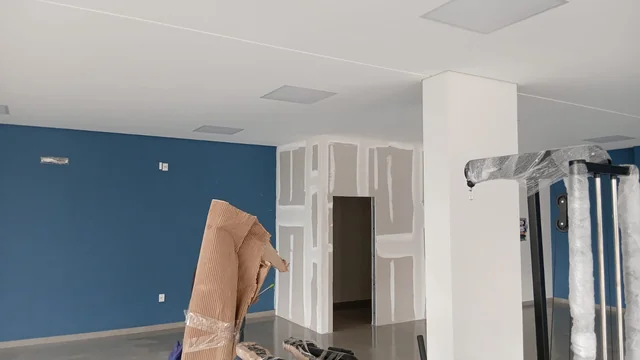 Divisória de drywall com juntas tratadas, em um ambiente com paredes azuis.