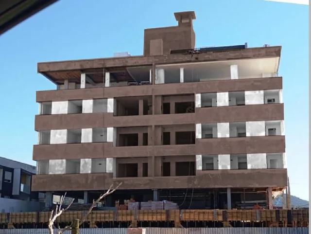 Edifício em etapa de alvenaria, com tijolos aparentes e estrutura de concreto.