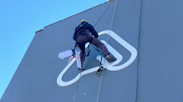 Profissional em cadeirinha diante de uma fachada azul durante o trabalho.