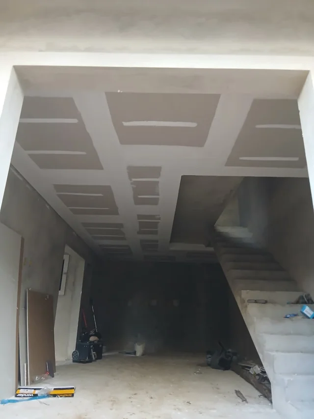Corredor em obra com forro de drywall e juntas em preparação.