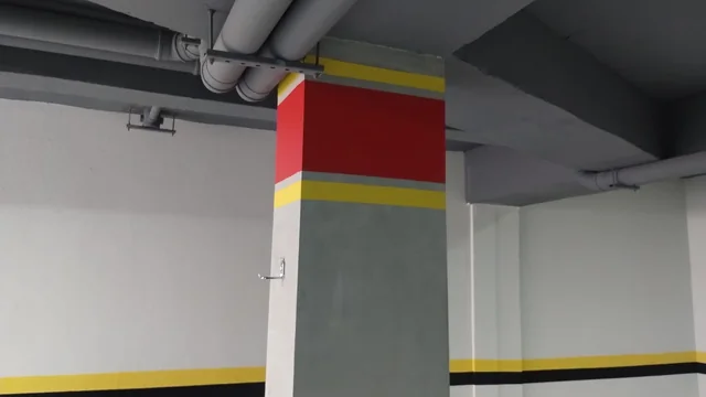 Garagem com pilares e paredes pintados em cinza, branco, vermelho e amarelo.