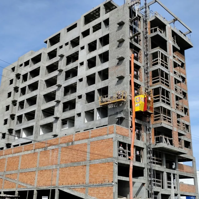 Edifício em construção, com alvenaria e estruturas de acesso na fachada.
