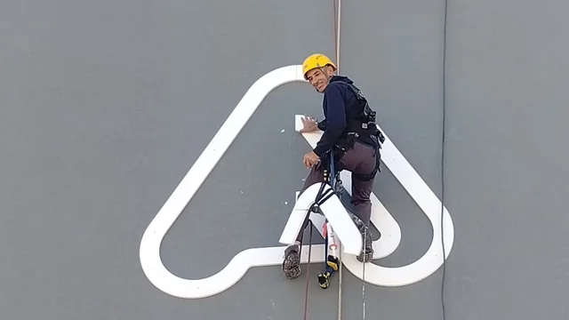 Profissional em acesso suspenso trabalhando no acabamento de uma fachada.