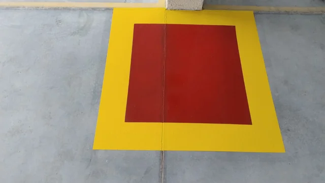 Área retangular de piso pintada em vermelho, com borda amarela.