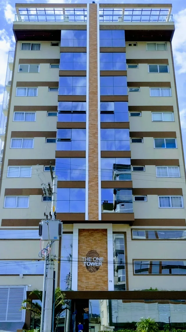 Vista frontal de edifício com faixas azuis e fachada clara.