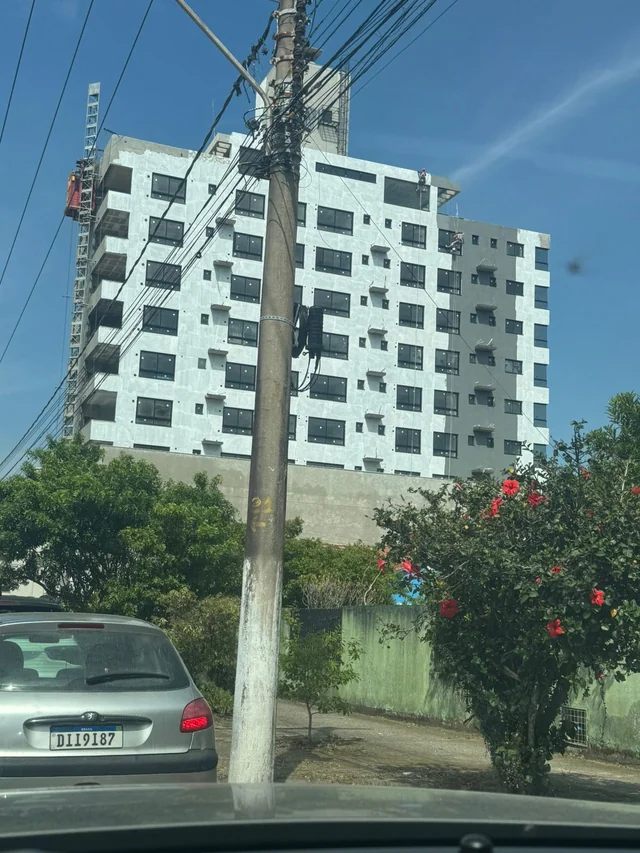 Edifício de fachada clara com varandas, visto da rua.