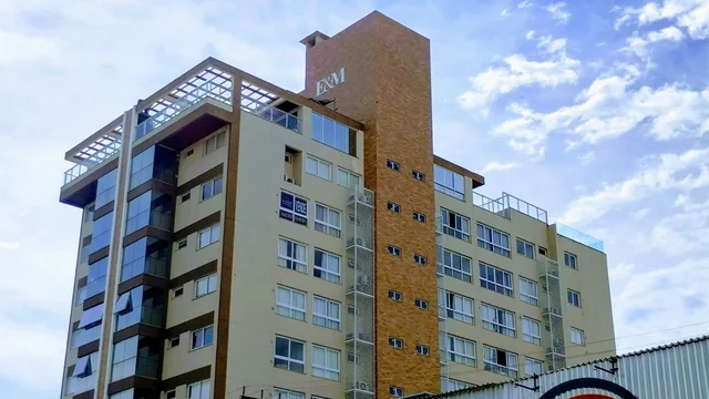 Edifício residencial com fachada amarela, marrom e detalhes brancos.