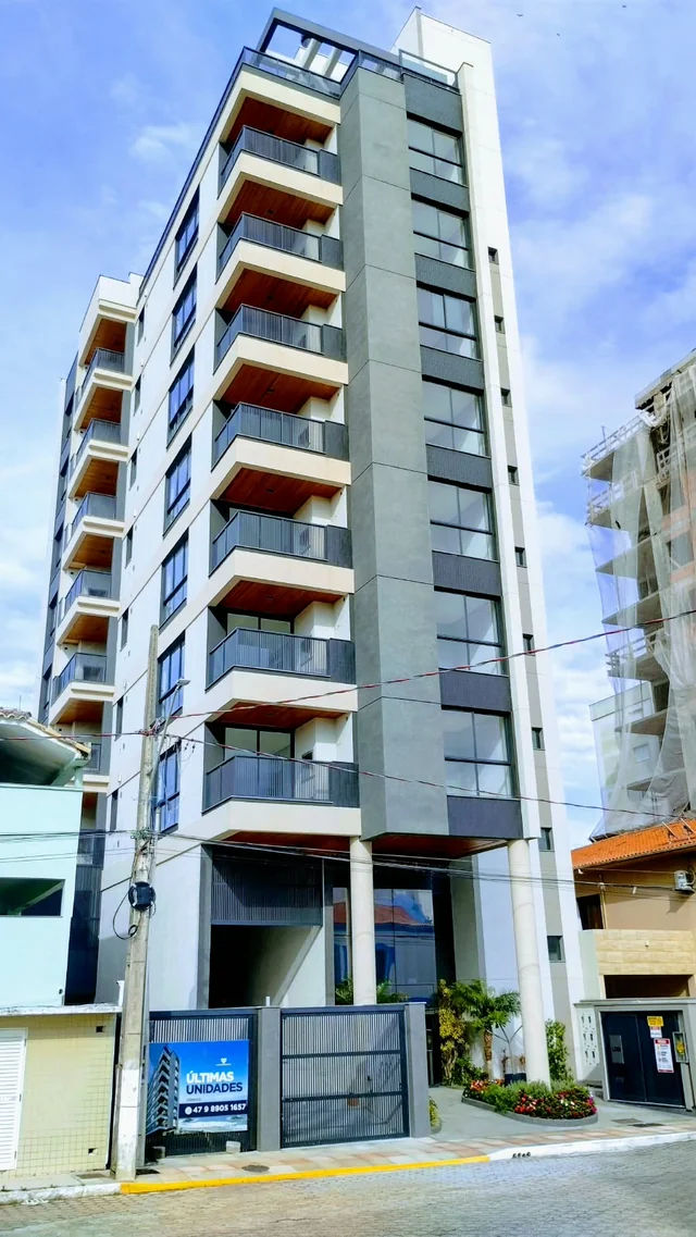 Edifício de fachada cinza com varandas e detalhes em tom avermelhado.