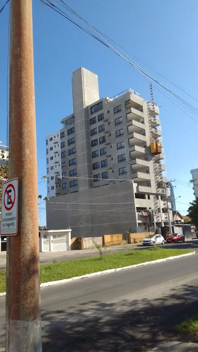 Edifício residencial de fachada clara, fotografado da rua.