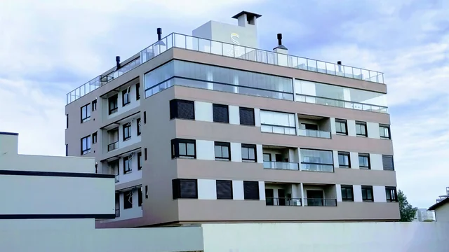 Edifício com pintura clara e cinza e janelas envidraçadas.