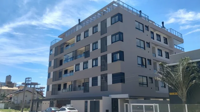Edifício residencial visto da esquina, com varandas e pintura em tons claros.