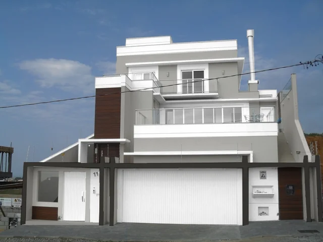 Casa de fachada branca e cinza, com varanda, portão e detalhes em marrom.